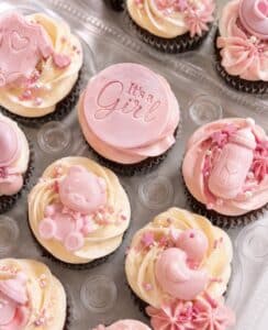 Custom baby shower cupcakes with pastel buttercream, bows, teddy bears, clouds, and themed decorations by Crumbly Cafe & Bakery NYC.