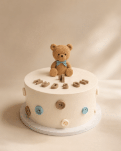 Baby Teddy Bear Cake with teddy bear topper, button details, and soft buttercream finish by Crumbly NYC