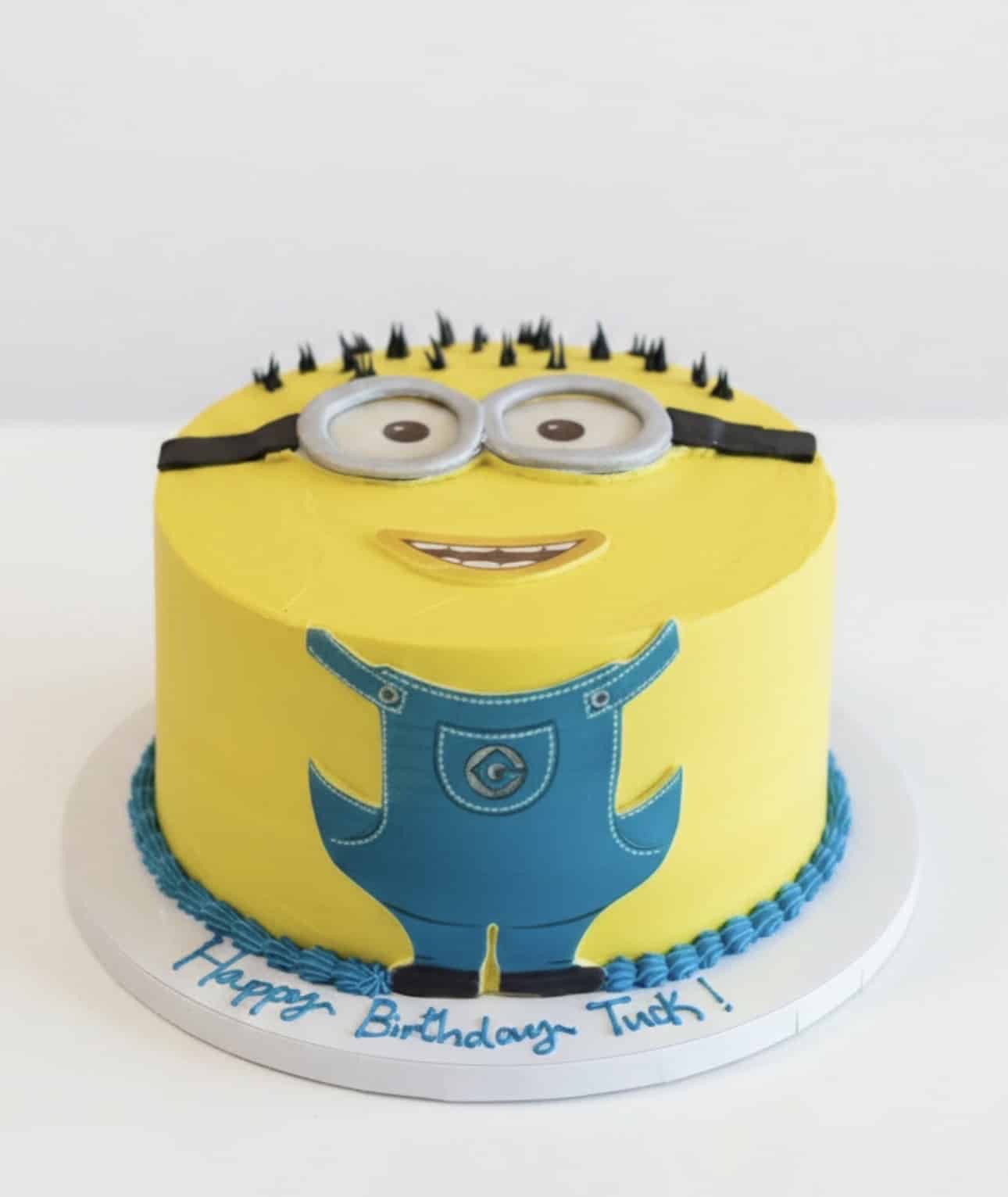 Minions Birthday Cake NYC with yellow buttercream, edible goggles, blue overalls, and custom birthday message by Crumbly.